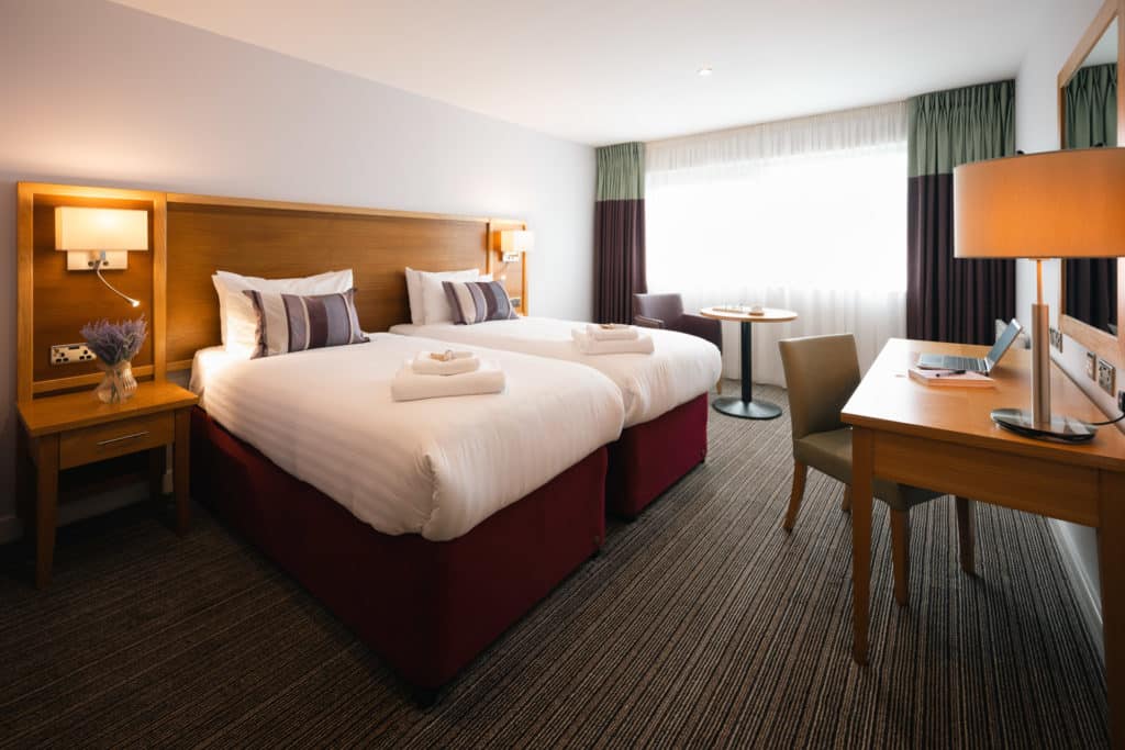 Twin Room in Aspect Hotel Park West with a laptop and notebook on the work desk.