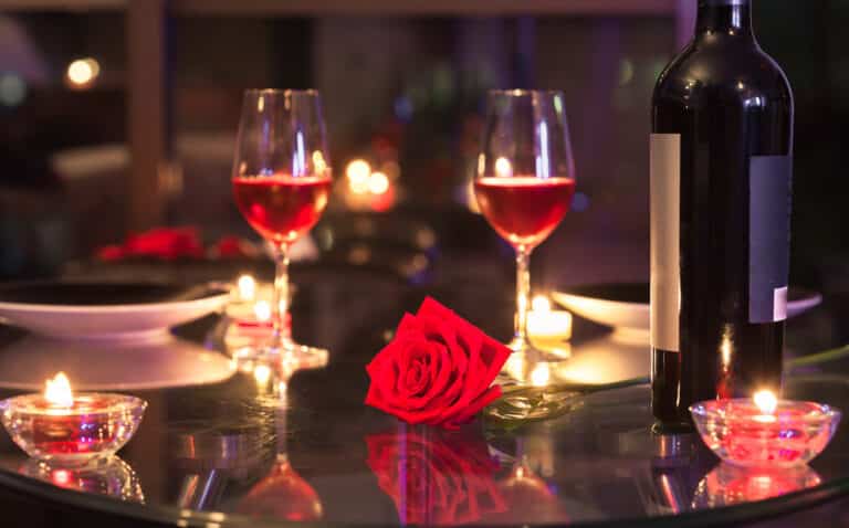Romantic dinner with a bottle of wine, wine glasses and a red rose